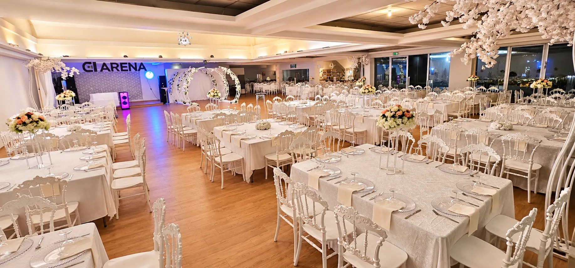 Festlich eingedeckter Saal mit weißen Tischen, Stühlen und Blumendekoration im Arena Adlersaal